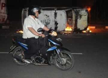 Warga Melintas di di Jalan Kimia, Salemba, Jakarta Pusat, Kamis malam (29/3) setelah pecah kerusuhan dalam unjuk rasa penolakan kenaikan harga bahan bakarf minyak (BBM) oleh mahasiswa UPI YAI dan UKI