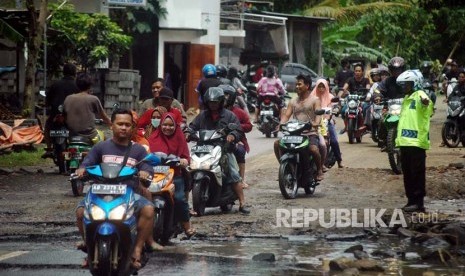 Warga melintas di jalan Sriharjo, Bantul, Yogyakarta yang terkikis akibat banjir. Pemkab Bantul menunggu rekomendasi pakar geologi untuk perbaiki jalan ambles Sriharjo