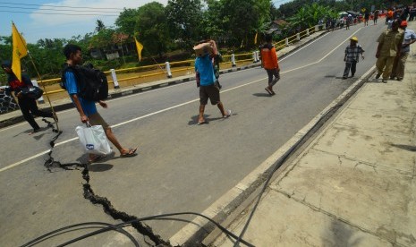 Warga melintas di jalan utama jembatan Putrapinggan, di Kecamatan Kalipucang, Kabupaten Pangandaran, Jawa Barat, Senin (10/10), setelah terjadi bencana longsor. 