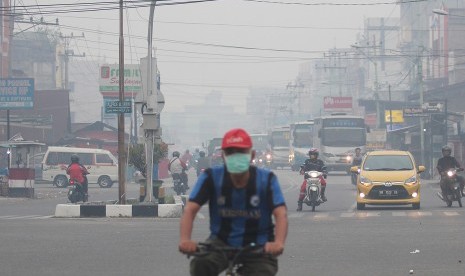 Warga melintas di jalan yang berkabut asap dari kebakaran hutan dan lahan di Kota Dumai, Dumai, Riau, Jumat (15/2/2019). 