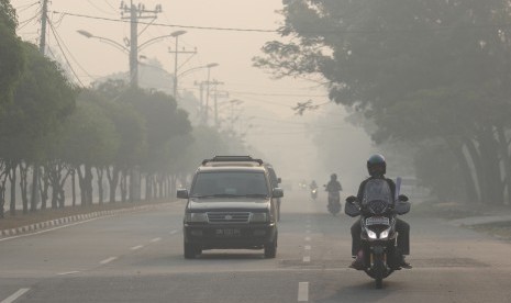 Kabut Asap Karhutla: Warga melintas di jalan yang berkabut asap pekat dari kebakaran hutan dan lahan (karhutla) di kota Dumai, Dumai. Riau, Sabtu (23/2/2019).