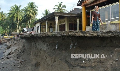 Warga melintas di jalan yang nyaris roboh akibat abrasi, di Pantai Ulakan, Padangpariaman, Sumatera Barat, Kamis (30/11).