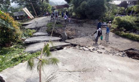 Warga melintas di jalan yang terbelah akibat pergerakan tanah di Bojong Koneng, Babakan Madang, Kabupaten Bogor, Jawa Barat. Pemkab Bogor memastikan kebutuhan warga terdampak pergerakan tanah akan terjamin.