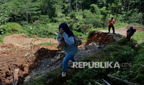 Warga melintas di jalan yang terdampak longsor, di Singajaya, Kabupaten Garut, Jawa Barat, Sabtu (9/1/2021). Intensitas hujan yang tinggi mengakibatkan jalan pedesaan longsor dan memutus akses penghubung antara Desa Karangagung dan Desa Singajaya sehingga aktivitas warga terganggu.