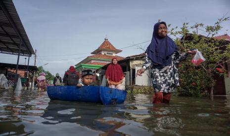 Warga melintas di jalan yang tergenang banjir rob di Degayu, Pekalongan, Jawa Tengah, Kamis (2/12/2021). Menurut warga setempat, banjir rob yang menggenangi wilayah itu terjadi sejak tiga pekan yang lalu yang membuat aktifitas perekonomian dan pendidikan warga menjadi terganggu, dengan ketinggian air antara 20-50 centimeter.