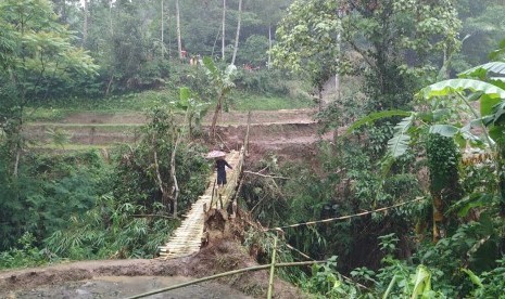 Warga melintas di jembatan darurat di Desa Indrajaya, Kecamatan Sukaratu, Kabupaten Tasikmalaya, Sabtu (29/2). Jembatan darurat itu berada sekira 200 meter dari jembatan utama di Desa Santanamekar, Kecamatan Cisayong, yang tertimbun longsor yang terjadi pada Jumat (28/2). 