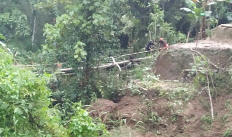 Warga melintas di jembatan darurat yang dibangun menuju wilayah yang terisolasi di dua desa di Kecamatan Cisayong dan Sukaratu, Kabupaten Tasikmalaya, Jumat (28/2) sore.