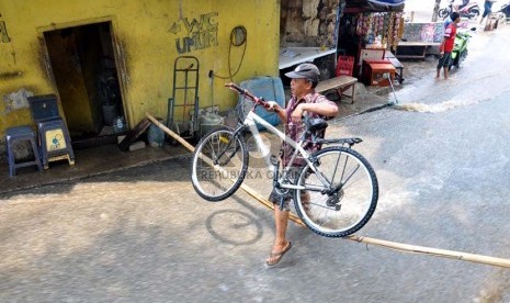 Warga melintas di kawasan pemukiman yang terendam banjir di Kampung Keramat, Condet, Jakarta Timur, Senin (8/10). (Rakhmawaty La'lang)