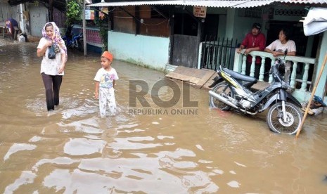 Warga melintas di kawasan pemukiman yang terendam banjir di Kampung Keramat, Condet, Jakarta Timur, Senin (8/10). (Rakhmawaty La'lang)