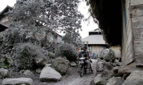   Warga melintas di pemukiman yang diselimuti debu vulkanik gunung Sinabung di Desa Mardingding, Karo, Sumut, Selasa (5/11).  (Antara/Rony Muharrman)