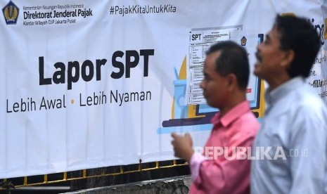 Warga melintas di samping spanduk himbauan pelaporan surat pemberitahuan (SPT) tahunan pajak di KPP Pratama Jakarta Tanah Abang Satu, Jakarta, Senin (19/3). 