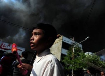 Warga melintas di tengah kebakaran yang melanda pemukiman di Jalan Lautze, kawasan Kartini, Jakarta Pusat, Selasa (7/2). 