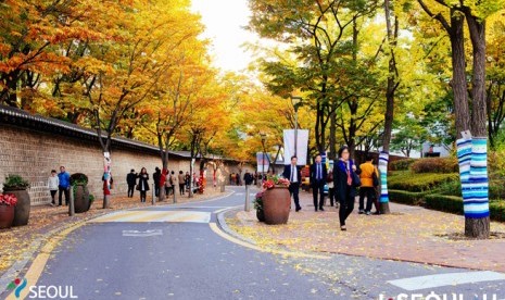 Warga melintas di trotoar saat musim gugur di Kota Seoul.