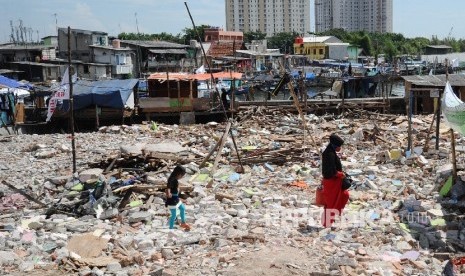  Warga melintas diantara puing sisa bangunan di kawasan Luar Batang, Penjaringan, Jakarta Utara , Selasa (5/3).(Republika/Tahta Aidilla)