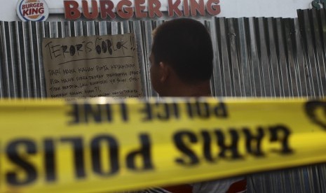 Warga melintas di depan restoran Burger King pascapenyerangan teroris di pos polisi dan sejumlah gedung di Sarinah Thamrin Jakarta, Jumat (15/1). 