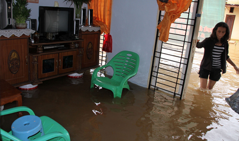 Warga melintas didepan rumahnya yang terendam banjir di Pekanbaru, Riau, Kamis (5/6). Derasnya hujan yang mengguyur Pekanbaru sekitarnya, membuat sungai Sail meluap yang mengakibatkan sedikitnya enam puluh rumah terendam banjir.