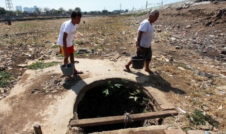 Warga melintas didepan sumur yang mengering di Jakarta, Senin (3/8).