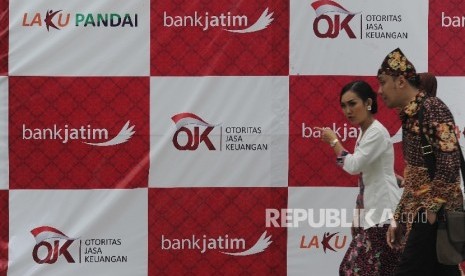  Warga melintas didepan tulisan Otoritas Jasa Keungan (OJK) saat peluncuran laku pandai Bank Jatim di Banyuwangi, Kamis (24/11). 