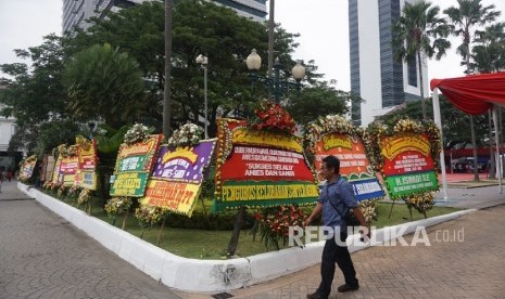 Warga melintas disamping karangan bunga yang berisi ucapan selamat kepada Anies Baswedan dan Sandiaga Uno di Balai Kota DKI Jakarta, Senin (16/10).