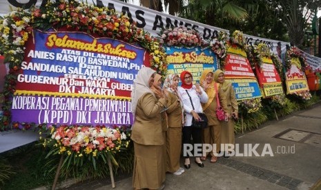 Warga melintas disamping karangan bunga yang berisi ucapan selamat kepada Anies Baswedan dan Sandiaga Uno di Balai Kota DKI Jakarta, Senin (16/10). 