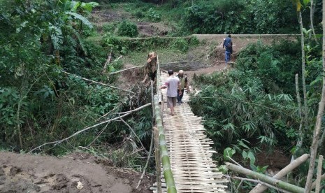 Warga melintas jembatan darurat di Desa Indrajaya, Kecamatan Sukaratu, Kabupaten Tasikmalaya, Senin (2/3). Jembatan utama yang berada di Desa Santanamekar, Kecamatan Cisayong, rusak terdampak longsor yang terjadi pada Jumat (28/2).