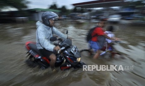 Warga melintas menggunakan motor saat banjir di Jalan Raya Baleendah, Kabupaten Bandung, Senin (3/10).