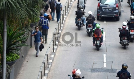 Warga melintas menggunakan trotoar di kawasan Jalan Sudirman, Jakarta Pusat, Jumat (20/11). 