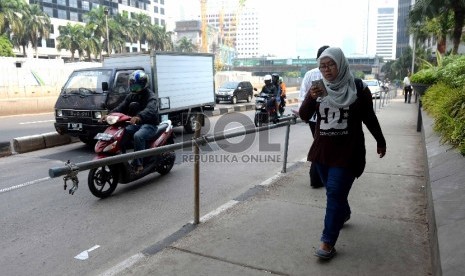 Warga melintas menggunakan trotoar di kawasan Jalan Sudirman, Jakarta Pusat, Jumat (20/11).