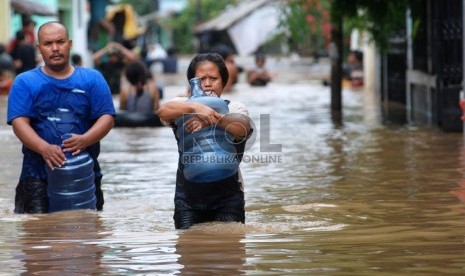   Warga melintas saat banjir merendam rumah mereka di Kampung Poncol, Kelurahan Bukit Duri, Kecamatan Tebet, Jakarta Selatan, Senin (24/12).  (Republika/Prayogi)