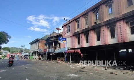 Warga melintasi bangunan yang rusak di Jayapura, Papua, Jumat (30/8/2019).