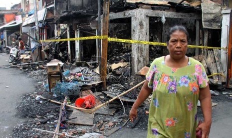   Warga melintasi bangunan yang terbakar akibat tawuran antarwarga di Johar Baru, Jakarta Pusat, Senin (18/11). (Republika/Yasin Habibi)