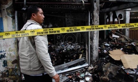   Warga melintasi bangunan yang terbakar akibat tawuran antarwarga di Johar Baru, Jakarta Pusat, Senin (18/11). (Republika/Yasin Habibi)