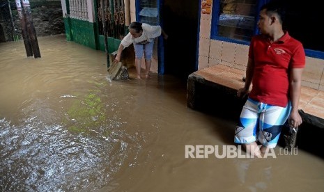 Warga melintasi banjir akibat luapan sungai Ciliwung di Kebon Pala II, Jakarta, Senin (13/2).