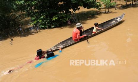 Warga melintasi banjir dengan menggunakan perahu di Desa Teupin Peuraho, Arongan Lam Balek, Aceh Barat, Aceh, Selasa (30/3/2021). Banjir yang disebabkan tingginya intensitas hujan dan meluapnya sungai krueng Woyla itu mengakibatkan puluhan rumah warga terendam banjir dengan ketinggian air 30 cm - 90 cm. 