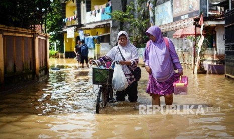 Warga melintasi banjir di Dayeuhkolot, Kabupaten Bandung.