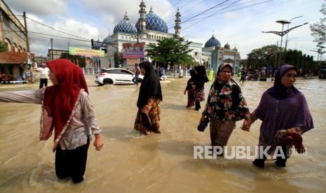 Warga melintasi banjir di Lhoksukon, Aceh Utara, Aceh, Senin (4/12)