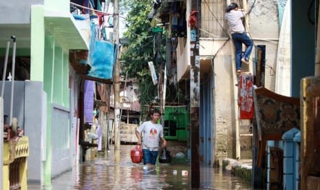 Warga melintasi banjir kiriman saat melanda kawasan Kampung Pulo, Jakarta Timur, Selasa (5/8). (Republika/ Yasin Habibi).