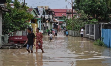 Warga melintasi banjir yang melanda permukiman warga di Kampung Baru, Palu, Sulawesi Tengah, Senin (29/4/2019). Banjir yang merendam puluhan rumah warga itu diakibatkan meluapnya air Sungai Palu akibat hujan lebat yang melanda wilayah hulu Sungai di Kabupaten Sigi. Kondisi itu dikhawatirkan akan semakin parah menyusul hujan deras yang masih terus terjadi dan mengakibatkan debit air Sungai Palu semakin meningkat. 