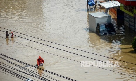 Warga melintasi banjir yang menggenangi Jalan Moh Toha, Kabupaten Bandung, Jawa Barat, Senin (8/4/2019). 