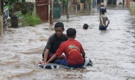 Warga melintasi banjir yang menggenangi kawasan Kampung Melayu, Jakarta, Senin (9/2).