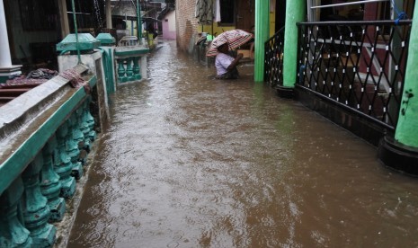 Warga melintasi banjir yang menggenangi perumahan di Kelurahan Ardirejo, Panji, Situbondo, Jawa Timur, Senin (27/11). Banjir juga melanda beberapa wilayah lain di Jawa Timur dampak dari cuaca ekstrem.