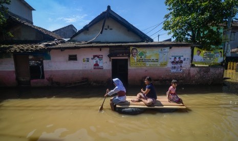 Warga melintasi banjir yang merendam Desa Bojongasih, Dayeuhkolot, Kabupaten Bandung, Jawa Barat, Jumat (29/3/2019).