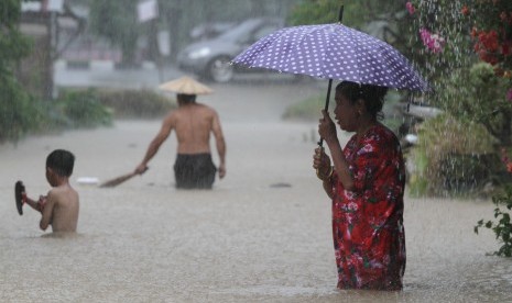 Warga melintasi banjir yang merendam wilayah permukimannya. (ilustrasi)