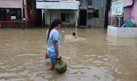 Warga melintasi banjir yang merendam permukiman penduduk, di kawasan pinggir Sungai Deli, di Medan, Sumatera Utara, Rabu (27/9). 