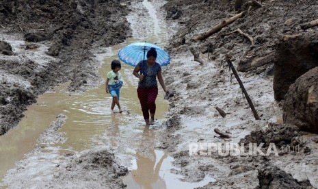 Ilustrasi. Warga melintasi bekas material tanah longsor di Desa Pattalikang, Kecamatan Manuju, Kabupaten Gowa, Sulawesi Selatan, Rabu (30/1/2019). Jalan Poros Malino di Gowa Masih Tertimbun Material Longsor