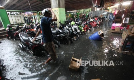 Warga melintasi genangan air di Pasar Blok G Tanah Abang, Jakarta, Senin (11/12). Hujan dengan intensitas tinggi disertai derainase saluran air yang buruk sehingga menyebabkan tergenangnya air di pasar tesebut. 