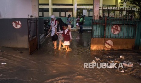 Warga melintasi genangan banjir bandang di SDN 224, Sukup Baru, Ujungberung, Bandung, Jawa Barat, Senin (1/4/2019).