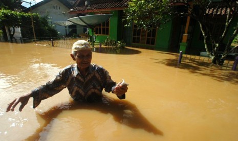 Warga melintasi genangan banjir di Desa Tanjungsari, Kabupaten Tasikmalaya, Jawa Barat, Kamis (17/).