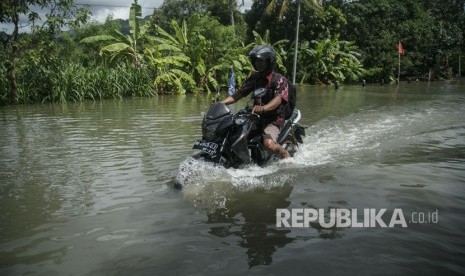 Warga melintasi genangan banjir di jalan Parangtritis, Donotirto, Kretek, Bantul, DI Yogyakarta.