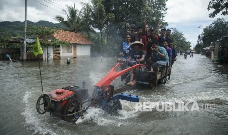 Warga melintasi genangan banjir di jalan Parangtritis, Donotirto, Kretek, Bantul, DI Yogyakarta, Senin (18/3/2019). 